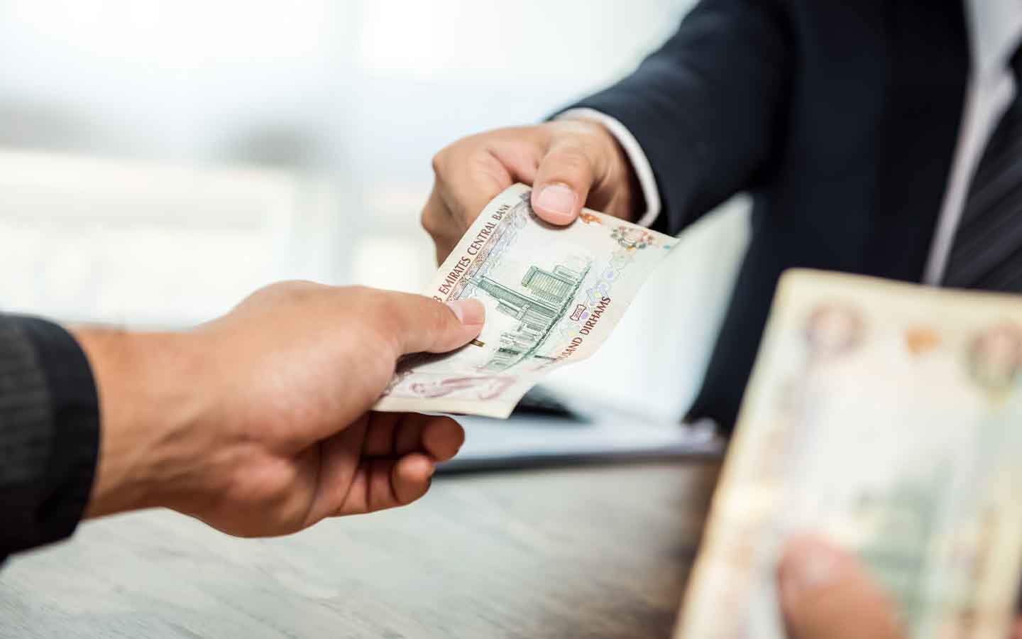 رجل يسلم رجل آخر عملة الدرهم الإماراتي