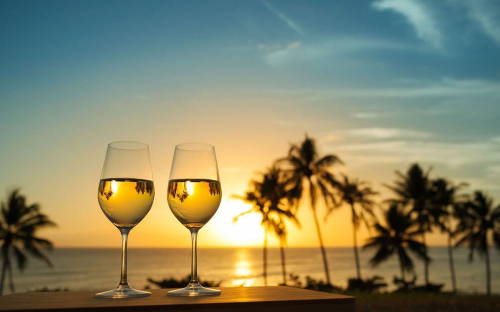 Glasses of liquor in the backdrop of sea shore and setting sea 