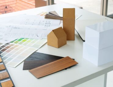 Designer presenting home layout plan with materials and furniture samples on workspace table