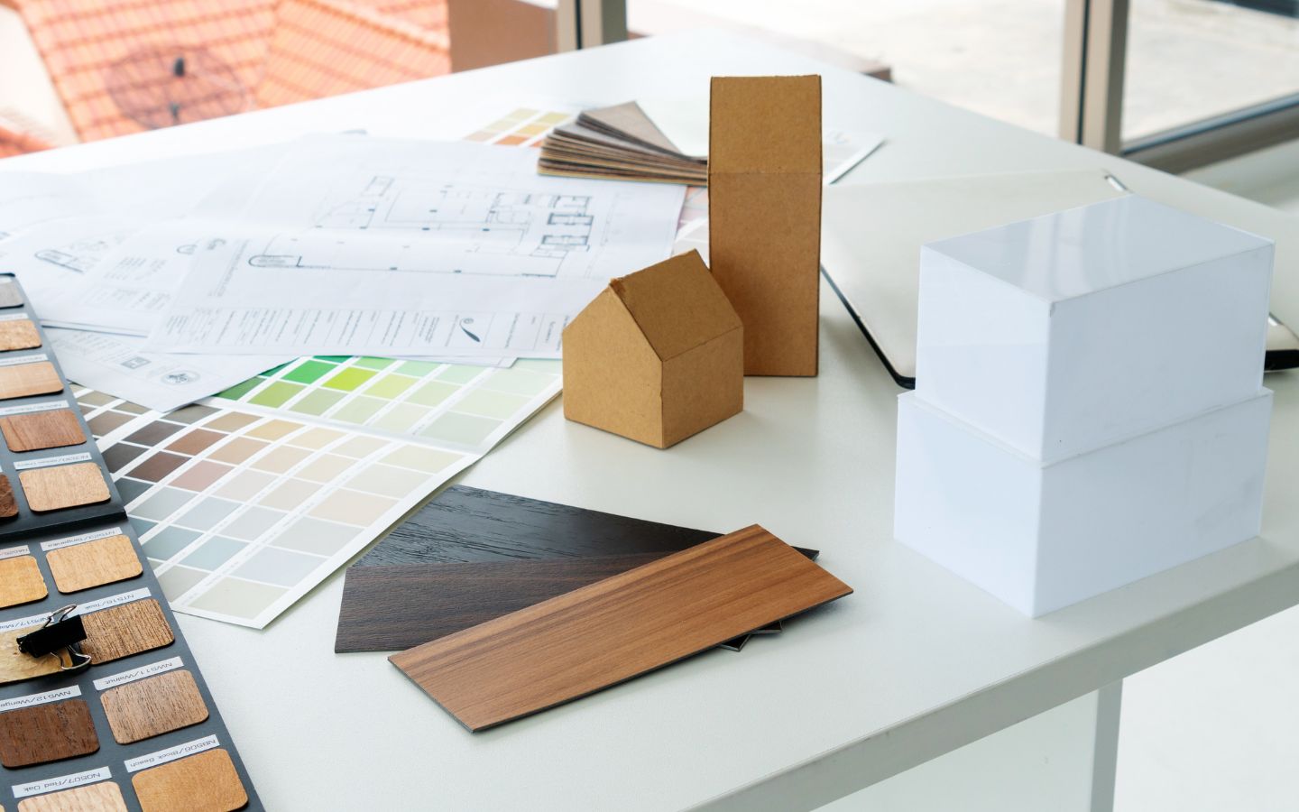 Designer presenting home layout plan with materials and furniture samples on workspace table