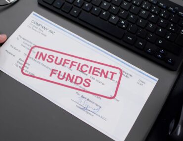 Image of a bounced cheque with a keyboard spectacles and a male hand