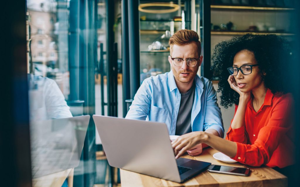 two people using laptop in a cafe