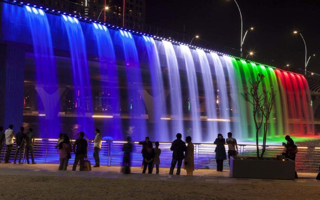 People viewing the fountain coloured by UAE flag lighting