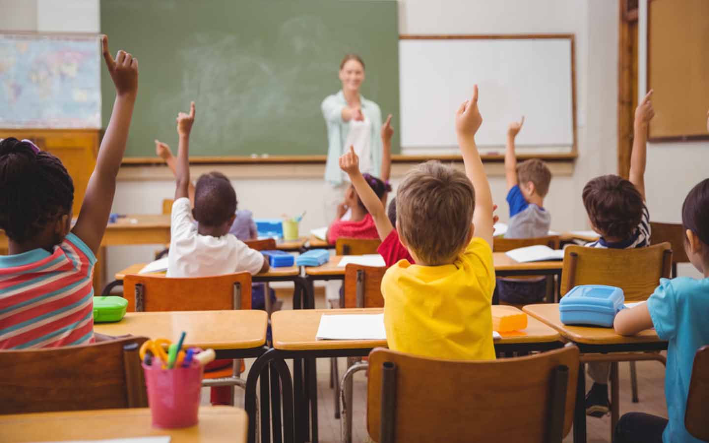 Students raise hands to answer question from the teacher
