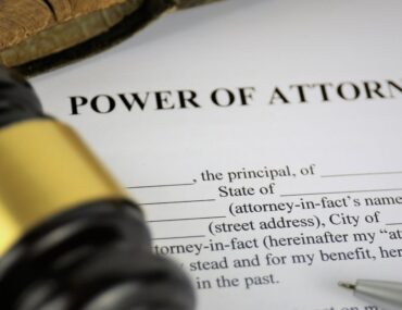 High-angle macro shot of a Power of Attorney legal form next to a wooden judge's gavel and a pen