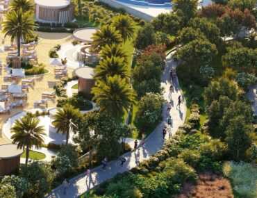 A scenic view of DAMAC Hills 2 featuring homes surrounded by greenery, lakes and walking paths.