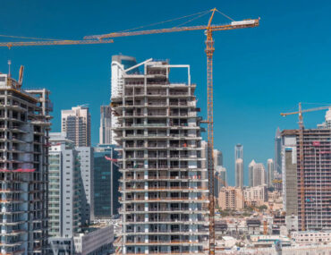 Construction site with unfinished high-rise buildings and cranes against the Dubai skyline