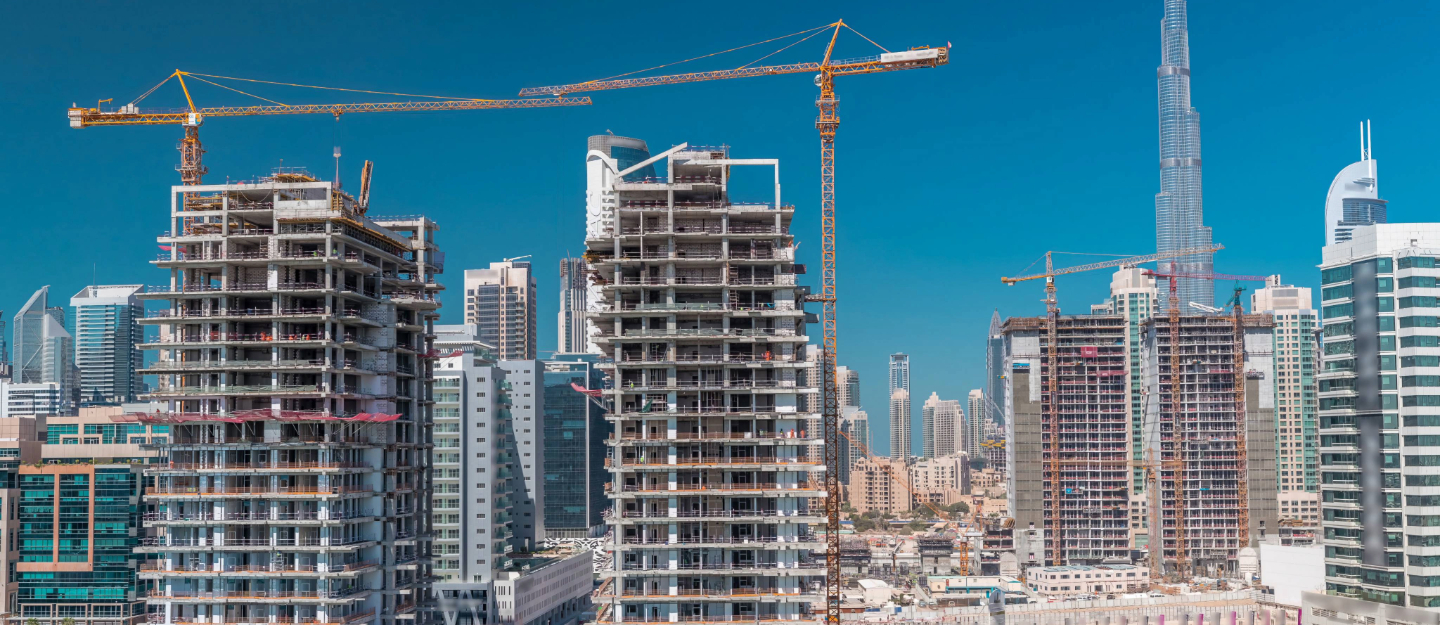 Construction site with unfinished high-rise buildings and cranes against the Dubai skyline