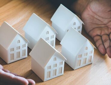 a number of miniature houses surrounded by a person's hand