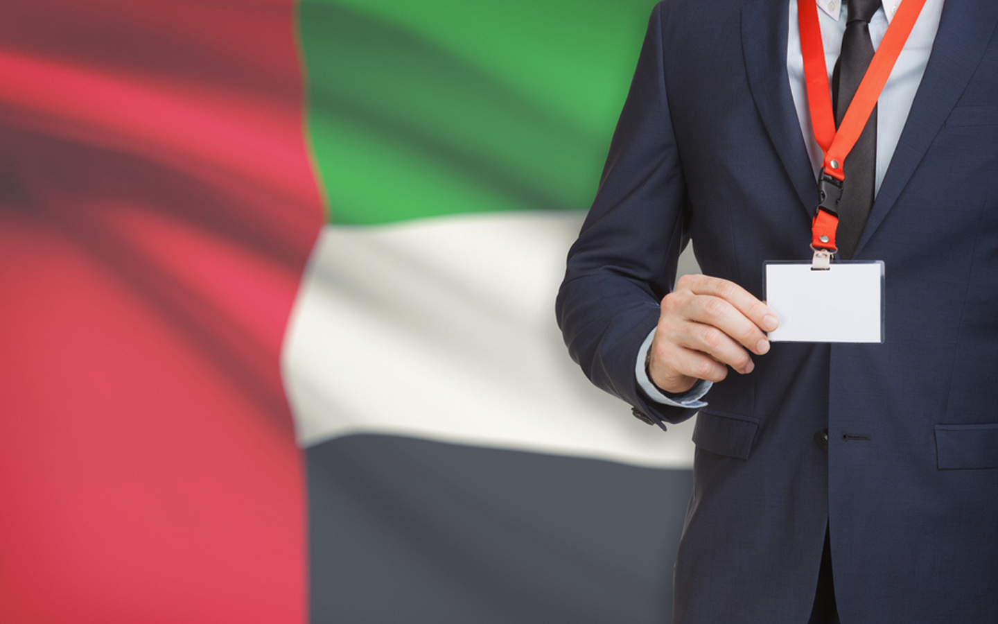 شخص يقف أمام العلم الإماراتي