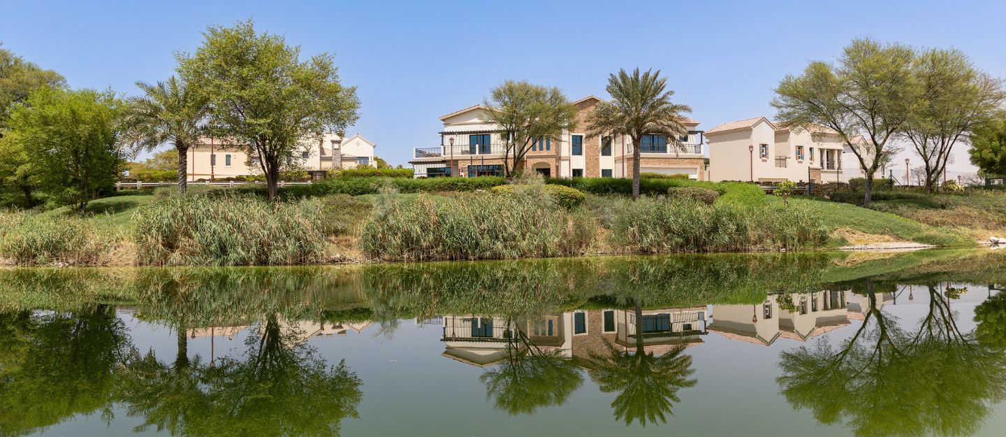 Scenic waterfront view of luxury villas and landscaped gardens in Jumeirah Golf Estates, Dubai