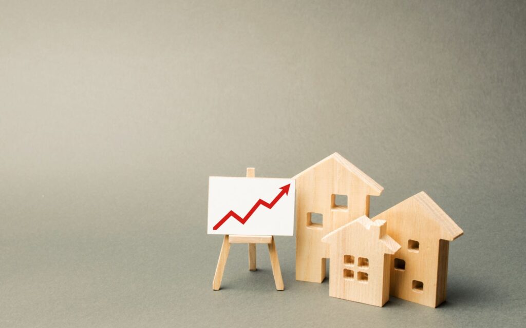 Wooden houses with a red upward graph showing real estate growth. 