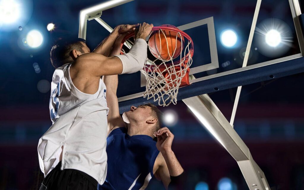 Men slam dunking in a basketball court