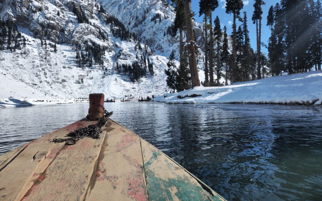 A wooden boat stretching into a clear turquoise lagoon surrounded by tropical greenery.