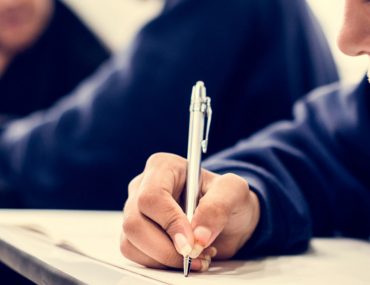 Female student with scarf writing in classroom