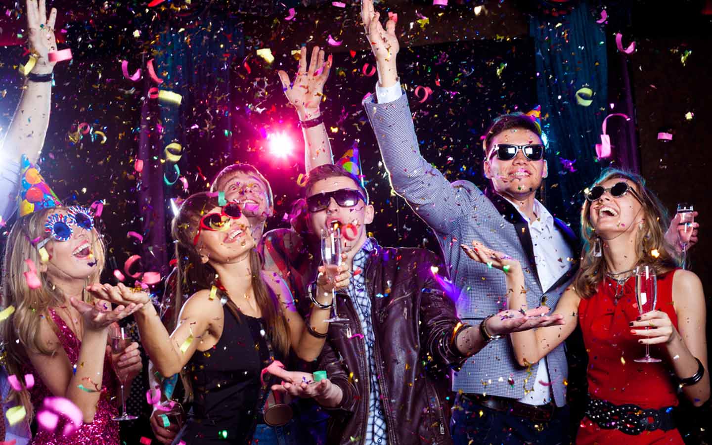 People dancing with drinks and confetti