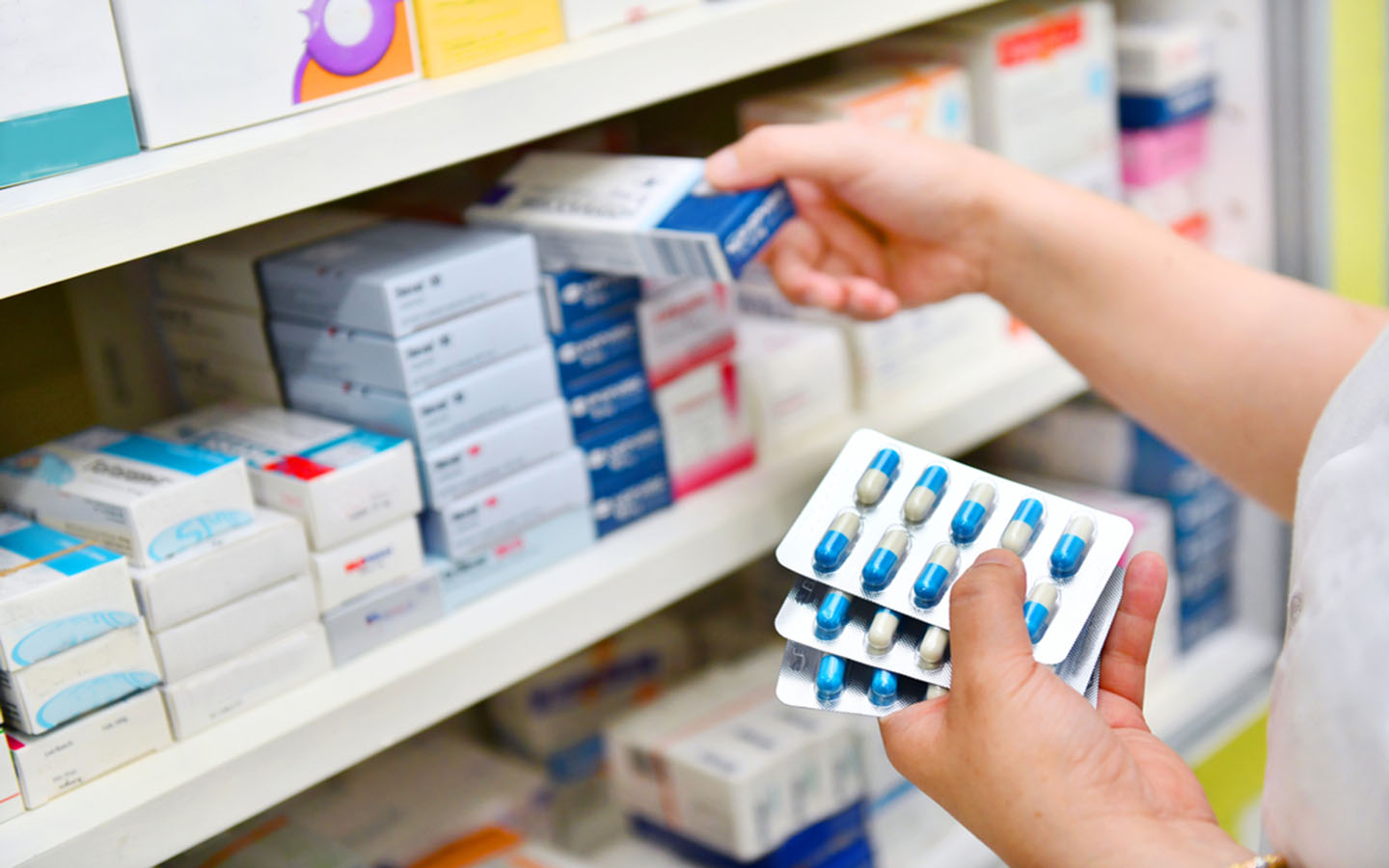 A pharmacist picking up medicine from the shelf