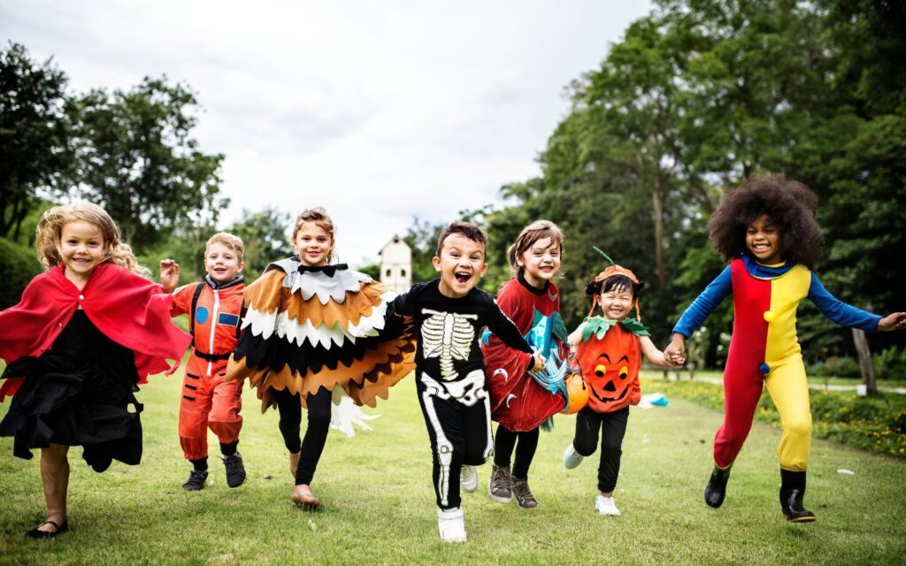 Kids running in a park with halloween costumes on