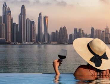 Visitors lounging by a popular infinity pool in Dubai at sunset.