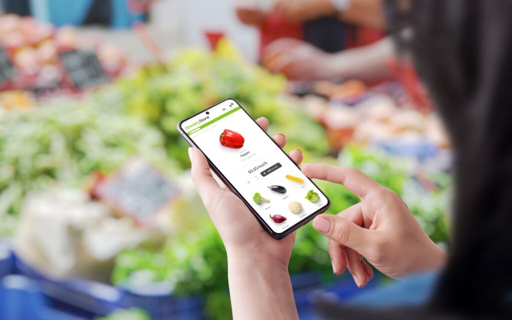 Hand holding smartphone with online grocery app showing Ramadan essentials.