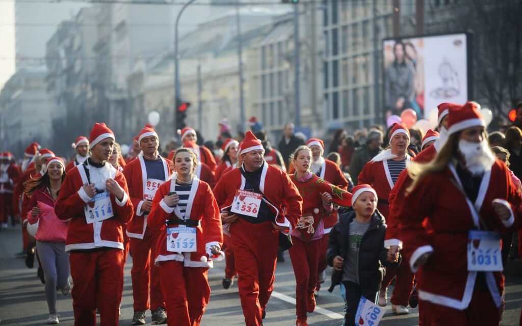 Families in Santa costumes running together at a festive Santa run 2025.