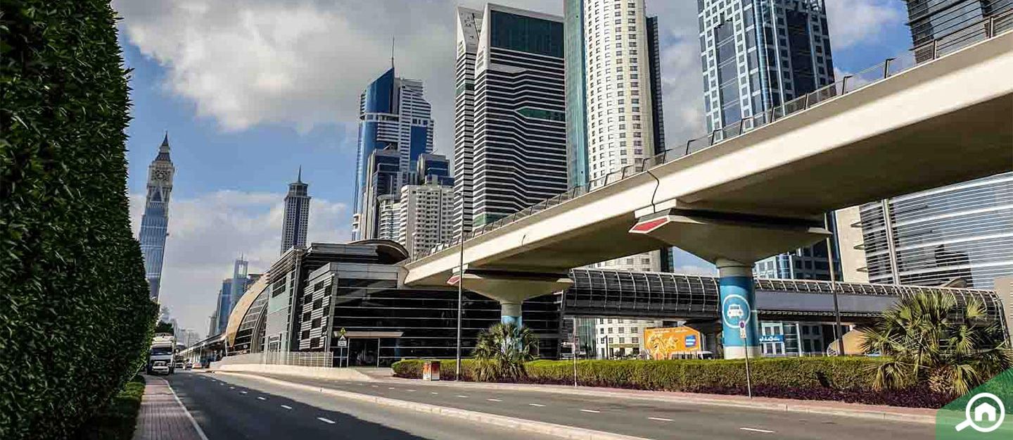 Street view of Sheikh Zayed Road featuring a Dubai Metro station with elevated tracks alongside Rose Rayhaan by Rotana