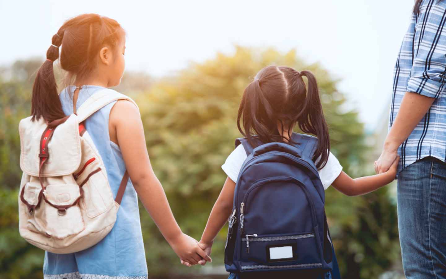 Two girls being taken to school by their guardian