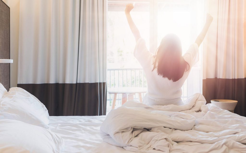 Woman waking up in hotel room in Abu Dhabi