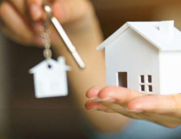 مجسم بيت في يد رجل