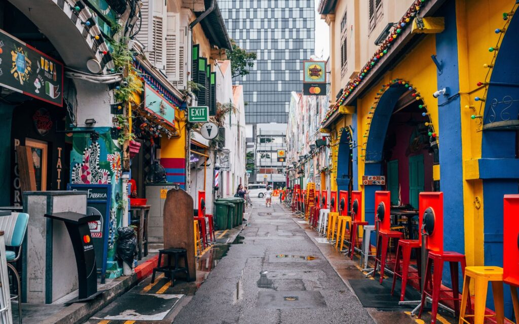 Busy shopping street with bright lights and retail stores in Singapore.