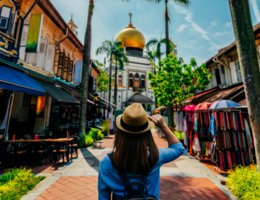 Tourist enjoying a busy shopping street with bright lights and retail stores in Singapore