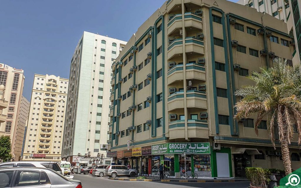 A street view of apartment buildings and Al Urooj grocery stores in Abu Shagara