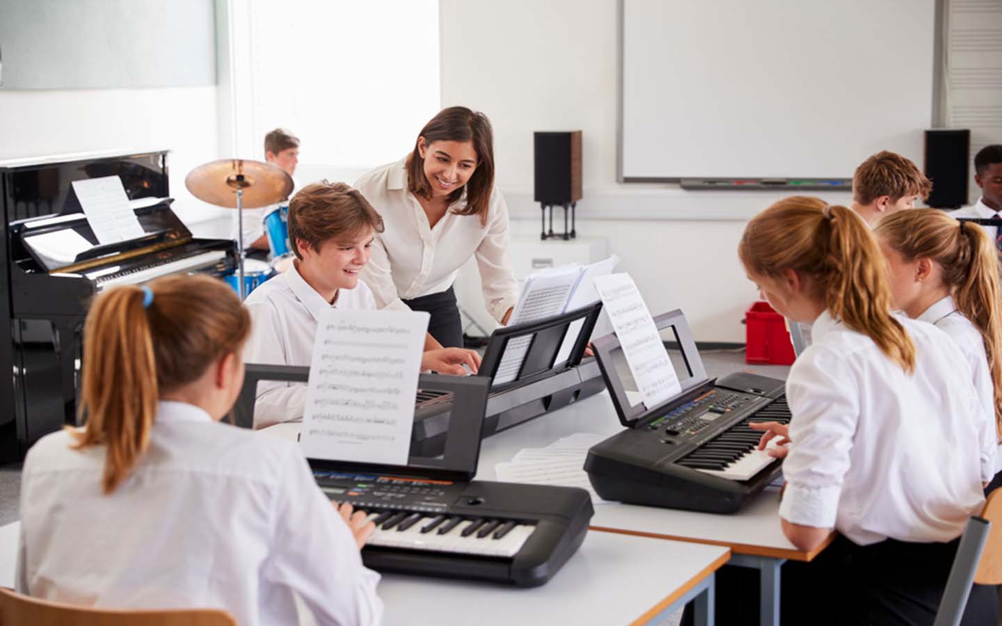 A teacher is explaining students about piano keys in a music class