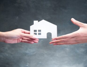 شخص يحمل ورقة على شكل منزل