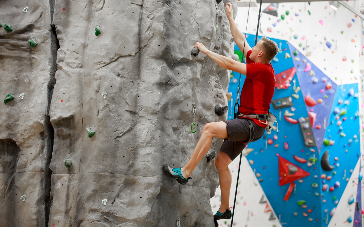 Man in a harness doing rock climbing in an indoor facility