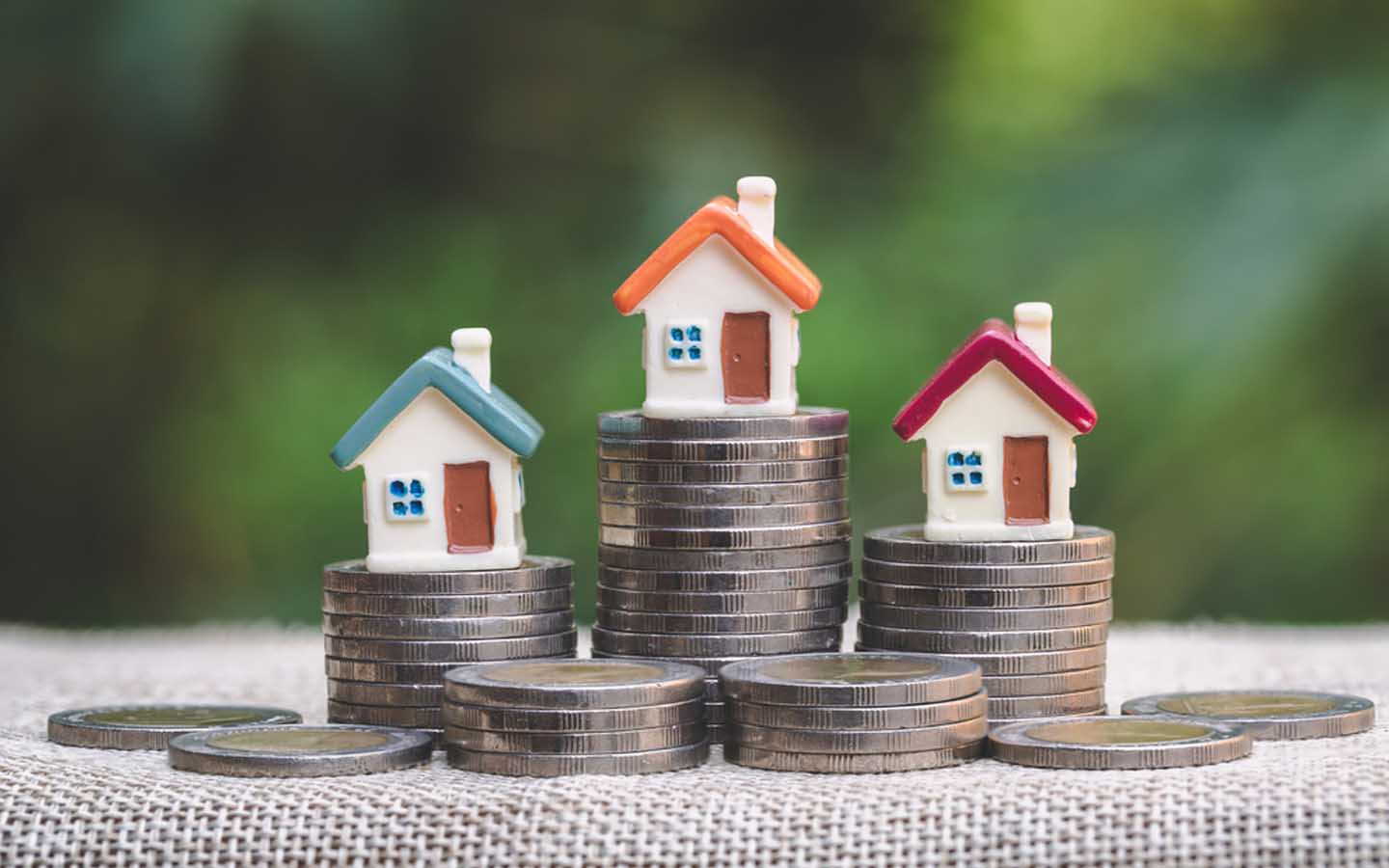 3 منازل صغيرة مع قطع نقدية تعبر عن مفهوم  إيداع الرهن العقاري في حساب الضمان دبي