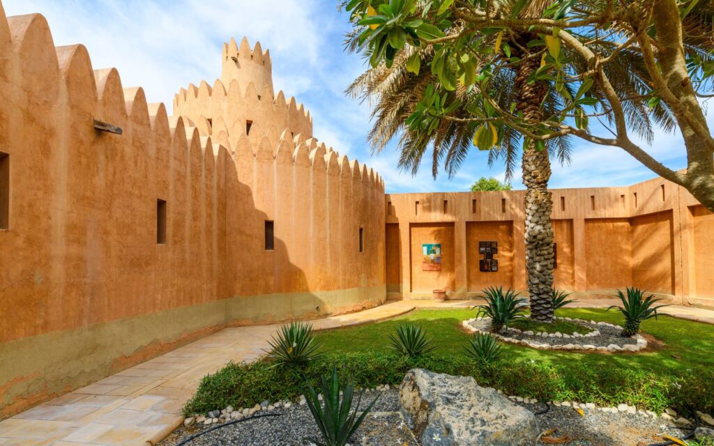 Lush landscaped garden at Al Ain Museum with pathways and palm trees.