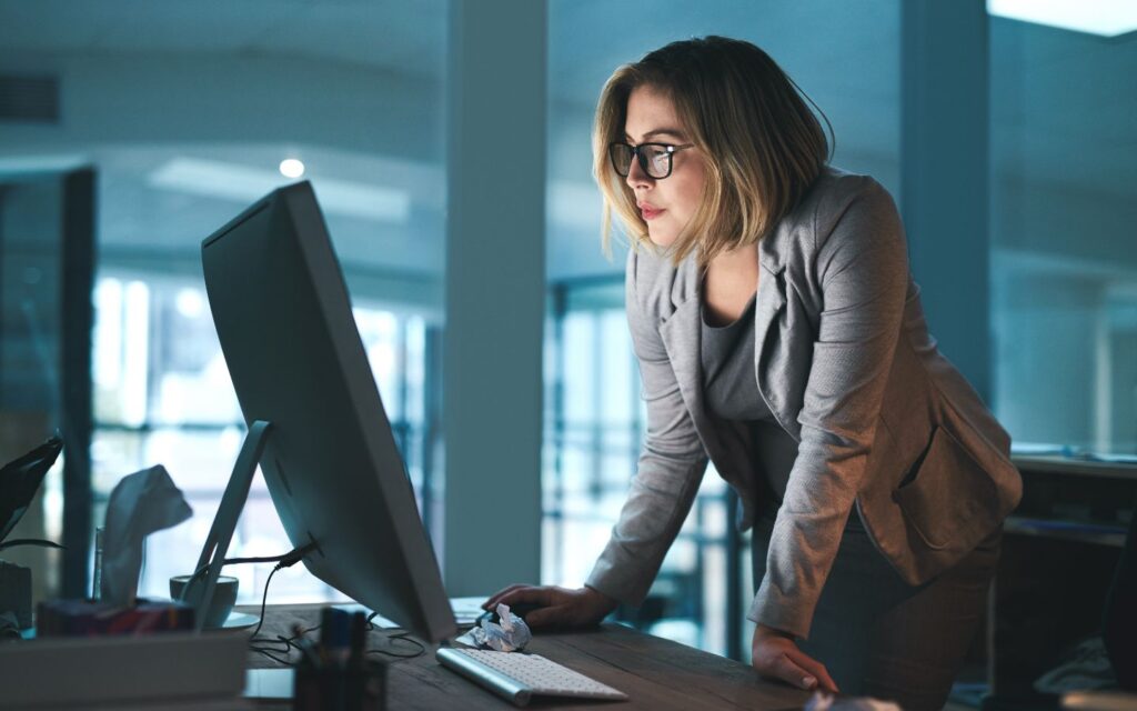 Businesswoman working late in office, focused on computer screen