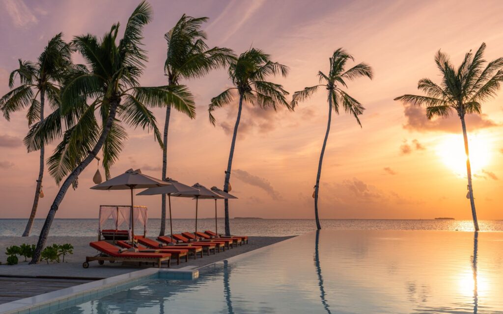 Poolside scene with sun loungers, umbrellas and clear water.