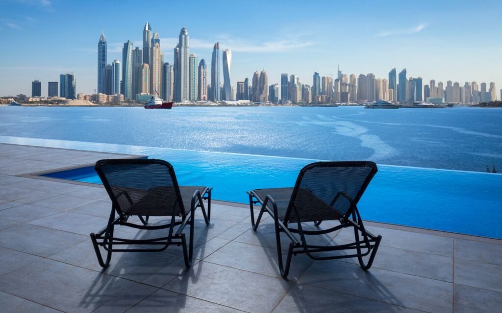 Luxury Dubai hotel infinity pool with guests relaxing and cocktails served poolside.
