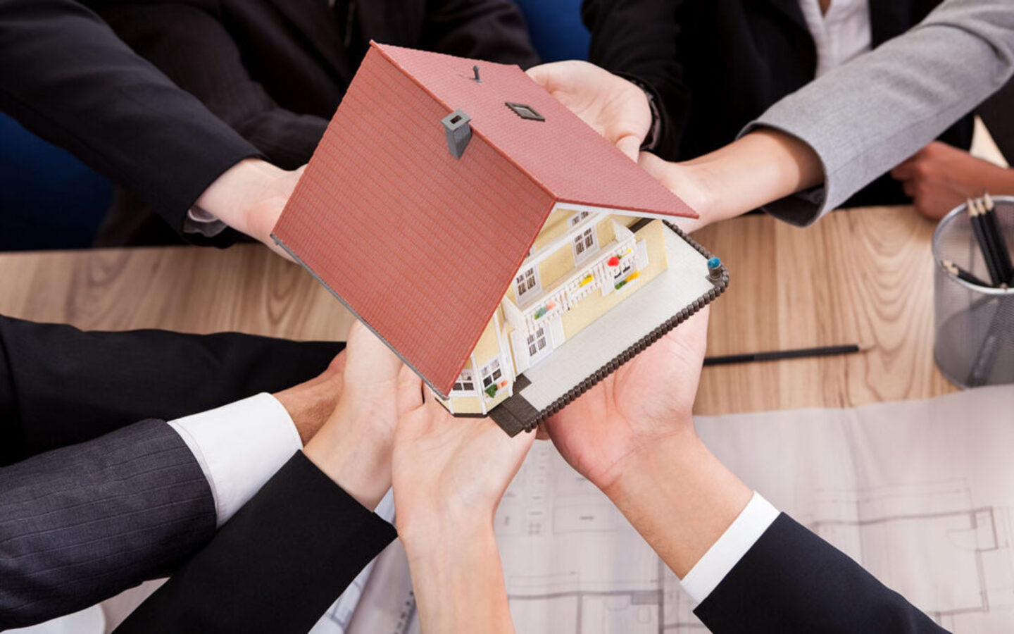 أيدٍ تحمل مجسم منزل