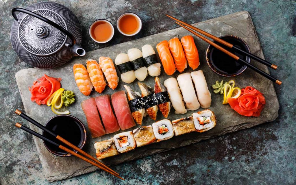 Assorted shushi and sashimi on a tray with chopsticks 