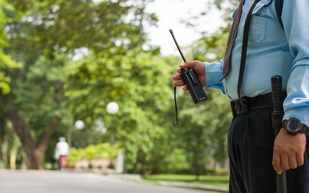 Security guard with a walkie-talkie monitoring an outdoor area