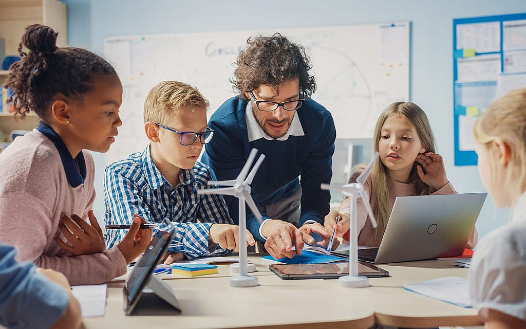 a teacher and students collaborating on a hands-on learning activity in a classroom