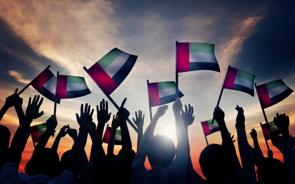 أشخاص يحملون علم الإمارات
